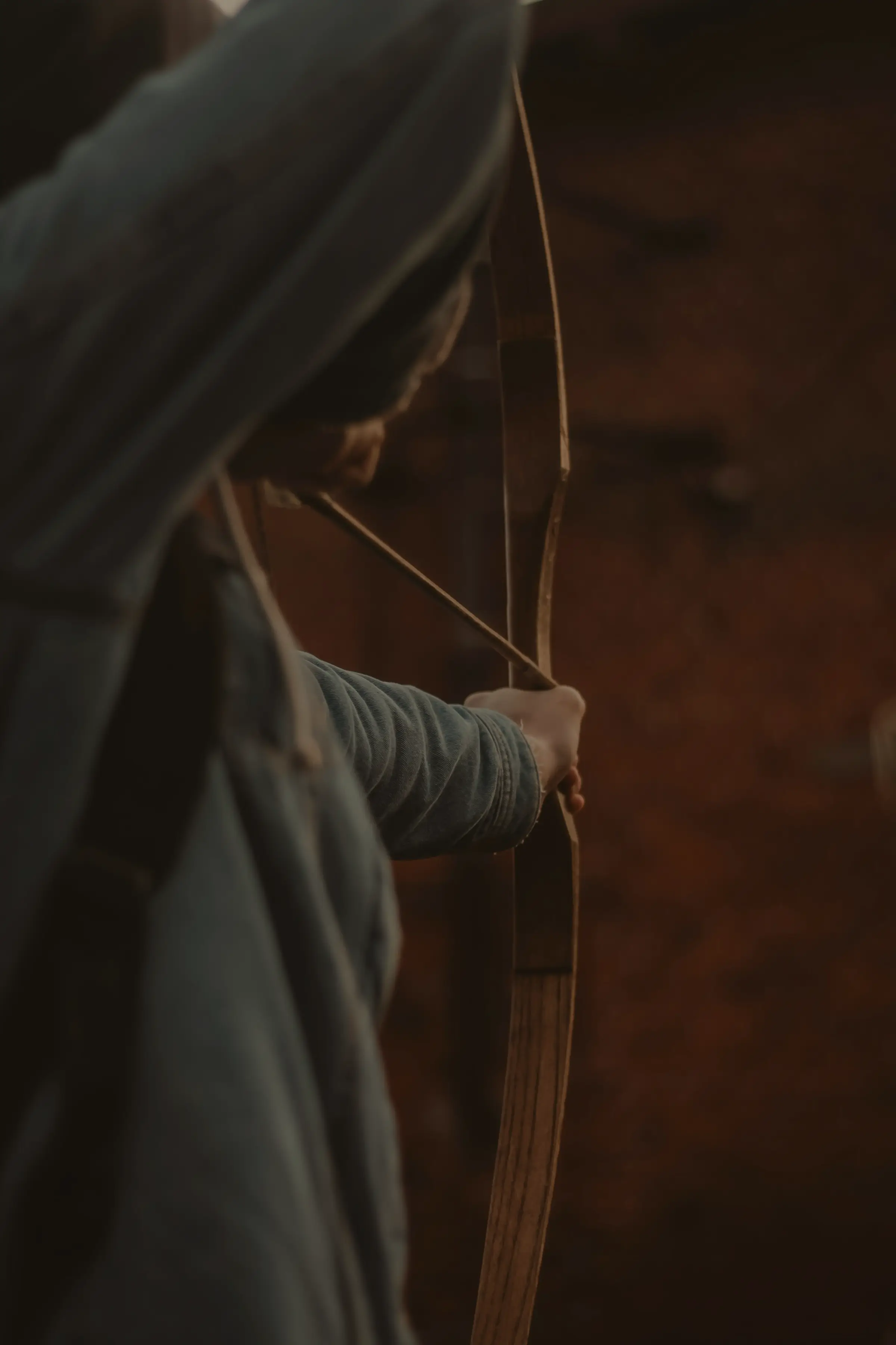 An archer at full draw at dusk